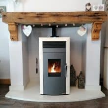 Commo 15 wood pellet boiler stove in fireplace with wooden mantle above.